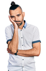 Hispanic man with ponytail wearing casual white shirt thinking looking tired and bored with depression problems with crossed arms.
