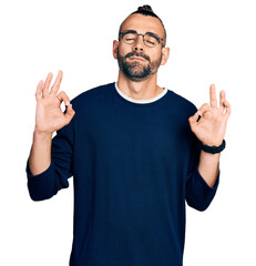 Hispanic man with ponytail wearing casual sweater and glasses relax and smiling with eyes closed doing meditation gesture with fingers. yoga concept.