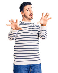 Young hispanic man wearing casual clothes afraid and terrified with fear expression stop gesture with hands, shouting in shock. panic concept.