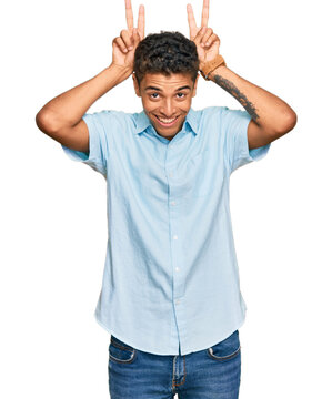 Young handsome african american man wearing casual clothes posing funny and crazy with fingers on head as bunny ears, smiling cheerful
