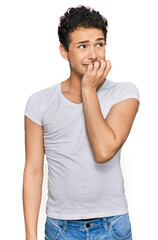 Young handsome man wearing casual white t shirt looking stressed and nervous with hands on mouth biting nails. anxiety problem.