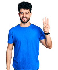 Young arab man with beard wearing casual blue t shirt showing and pointing up with fingers number three while smiling confident and happy.