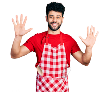 Young arab man with beard wearing cook apron showing and pointing up with fingers number ten while smiling confident and happy.