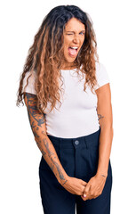 Fototapeta premium Young hispanic woman with tattoo wearing casual white tshirt winking looking at the camera with sexy expression, cheerful and happy face.