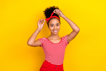 Photo of shiny sweet lady wear striped red t-shirt tying hairband isolated yellow color background