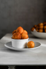 Rosy balls of delicious doughnuts in a white ceramic bowl on the table. Traditional oriental sweet food and treats for the Hanukkah.                                                                  