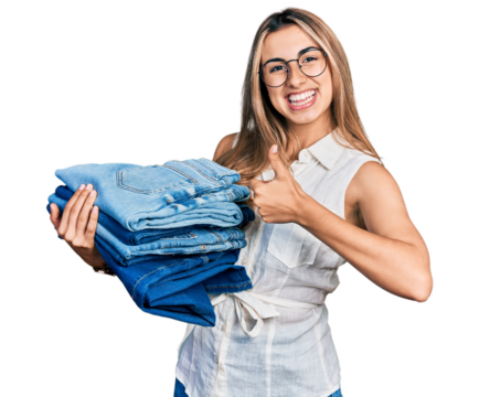 Hispanic young woman holding stack of folded jeans smiling happy and positive, thumb up doing excellent and approval sign