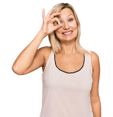 Fototapeta premium Middle age caucasian woman wearing casual clothes doing ok gesture with hand smiling, eye looking through fingers with happy face.
