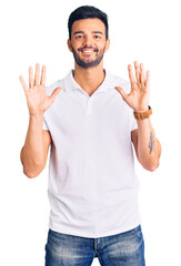 Naklejka premium Young handsome hispanic man wearing casual clothes showing and pointing up with fingers number ten while smiling confident and happy.