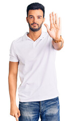 Young handsome hispanic man wearing casual clothes doing stop sing with palm of the hand. warning expression with negative and serious gesture on the face.