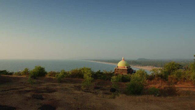 Beautiful sunset landscape view from moving camera on Gokarna main beach with Shri Bharateswara Temple from hilltop viewpoint. South India, Karnataka