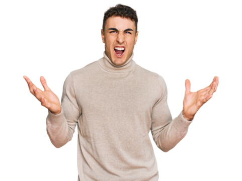 Hispanic young man wearing casual turtleneck sweater crazy and mad shouting and yelling with aggressive expression and arms raised. frustration concept.