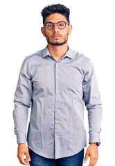 Fototapeta premium Handsome latin american young man wearing business clothes and glasses with serious expression on face. simple and natural looking at the camera.