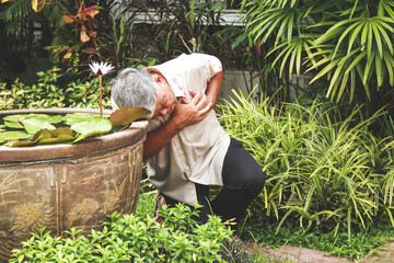 Asian elderly man acute heartache His head leaned against the edge of the lotus basin. Elderly...