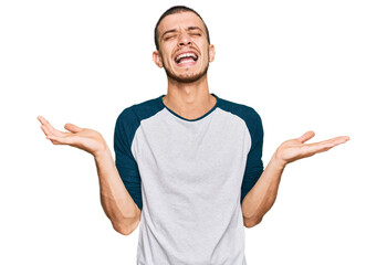 Fototapeta premium Hispanic young man wearing casual clothes celebrating mad and crazy for success with arms raised and closed eyes screaming excited. winner concept