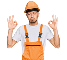 Hispanic young man wearing handyman uniform and safety hardhat relax and smiling with eyes closed doing meditation gesture with fingers. yoga concept.