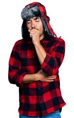 Fototapeta premium Hispanic young man with beard wearing fluffy earmuff hat feeling unwell and coughing as symptom for cold or bronchitis. health care concept.