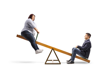 Corpulent woman playing on a seesaw with a young man