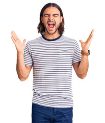 Young handsome man wearing casual clothes celebrating mad and crazy for success with arms raised...
