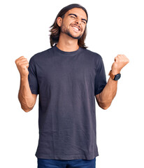 Fototapeta premium Young handsome man wearing casual clothes very happy and excited doing winner gesture with arms raised, smiling and screaming for success. celebration concept.