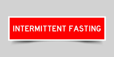 Red color square shape sticker label with word intermittent fasting on gray background