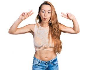 Young caucasian woman doing victory sign and peace gesture making fish face with mouth and squinting eyes, crazy and comical.