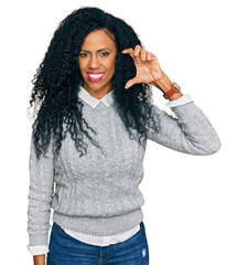 Middle age african american woman wearing casual clothes smiling and confident gesturing with hand doing small size sign with fingers looking and the camera. measure concept.