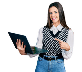 Young brunette teenager working using computer laptop smiling happy pointing with hand and finger