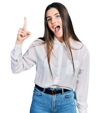 Young brunette teenager wearing business white shirt pointing finger up with successful idea. exited and happy. number one.