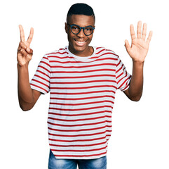 Young african american man wearing casual t shirt and glasses showing and pointing up with fingers number seven while smiling confident and happy.