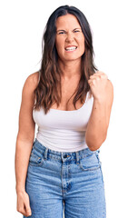 Young beautiful brunette woman wearing casual sleeveless t-shirt angry and mad raising fist frustrated and furious while shouting with anger. rage and aggressive concept.