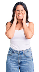 Fototapeta premium Young beautiful brunette woman wearing casual sleeveless t-shirt covering ears with fingers with annoyed expression for the noise of loud music. deaf concept.