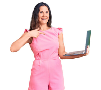 Young beautiful brunette woman working using laptop pointing finger to one self smiling happy and proud