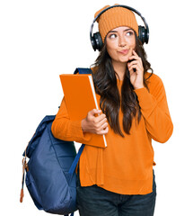 Beautiful brunette young woman wearing student backpack and holding books serious face thinking...