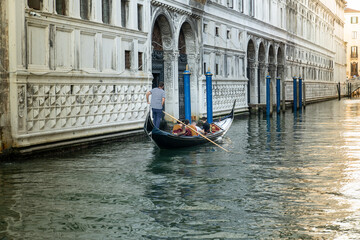 Fototapeta na wymiar Traveling with a traditional gondola through the narrow ancient canals of Venice (Venedik) italy.