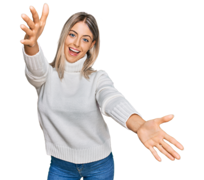 Beautiful blonde woman wearing casual turtleneck sweater looking at the camera smiling with open arms for hug. cheerful expression embracing happiness.