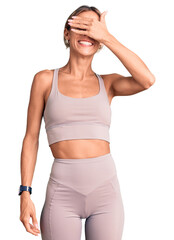Beautiful caucasian woman wearing sportswear smiling and laughing with hand on face covering eyes for surprise. blind concept.