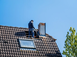 A team of roofers working on a building rooftop exterior, repairing and insulating the chimney under a clear sky