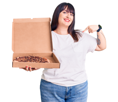 Young plus size woman holding delivery pizza box pointing finger to one self smiling happy and proud