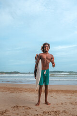 Fototapeta na wymiar Surfing.Sri Lankans, Indians surfers on the ocean coast with a surfboard, athletic tanned body, smiling and running with a surfboard on the beach in sunny summer