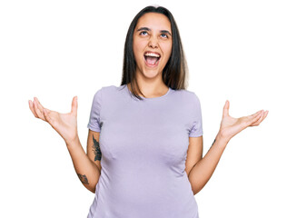 Young hispanic woman wearing casual clothes crazy and mad shouting and yelling with aggressive expression and arms raised. frustration concept.