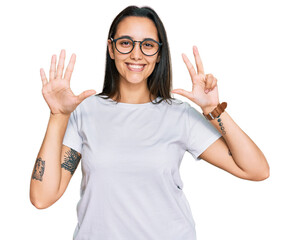 Young hispanic woman wearing casual white t shirt showing and pointing up with fingers number eight while smiling confident and happy.