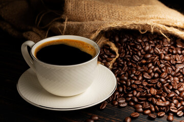 Black coffee or hot tea in a cappuccino espresso cup, breakfast food with coffee beans on a wooden table Isolated on a dark background, top view