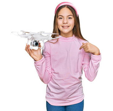 Beautiful brunette little girl using drone pointing finger to one self smiling happy and proud