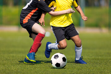 Two soccer players running and kicking a soccer ball. Legs of two young multiracial football...