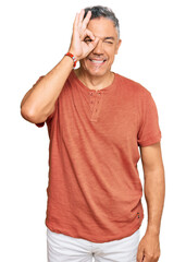 Handsome middle age man wearing casual clothes doing ok gesture with hand smiling, eye looking through fingers with happy face.