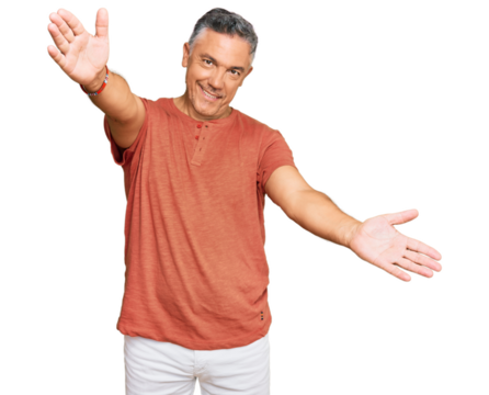Handsome middle age man wearing casual clothes looking at the camera smiling with open arms for hug. cheerful expression embracing happiness.