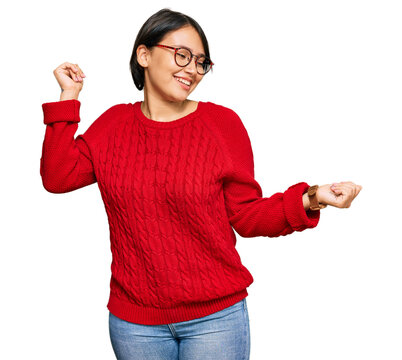 Young beautiful hispanic woman with short hair wearing casual sweater and glasses dancing happy and cheerful, smiling moving casual and confident listening to music