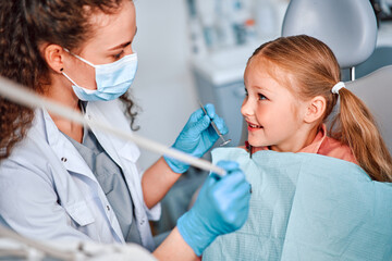 Children's dentistry. A child is sitting in a dental chair and talking to a nurse.