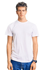Obraz premium Young handsome man wearing casual white tshirt relaxed with serious expression on face. simple and natural looking at the camera.